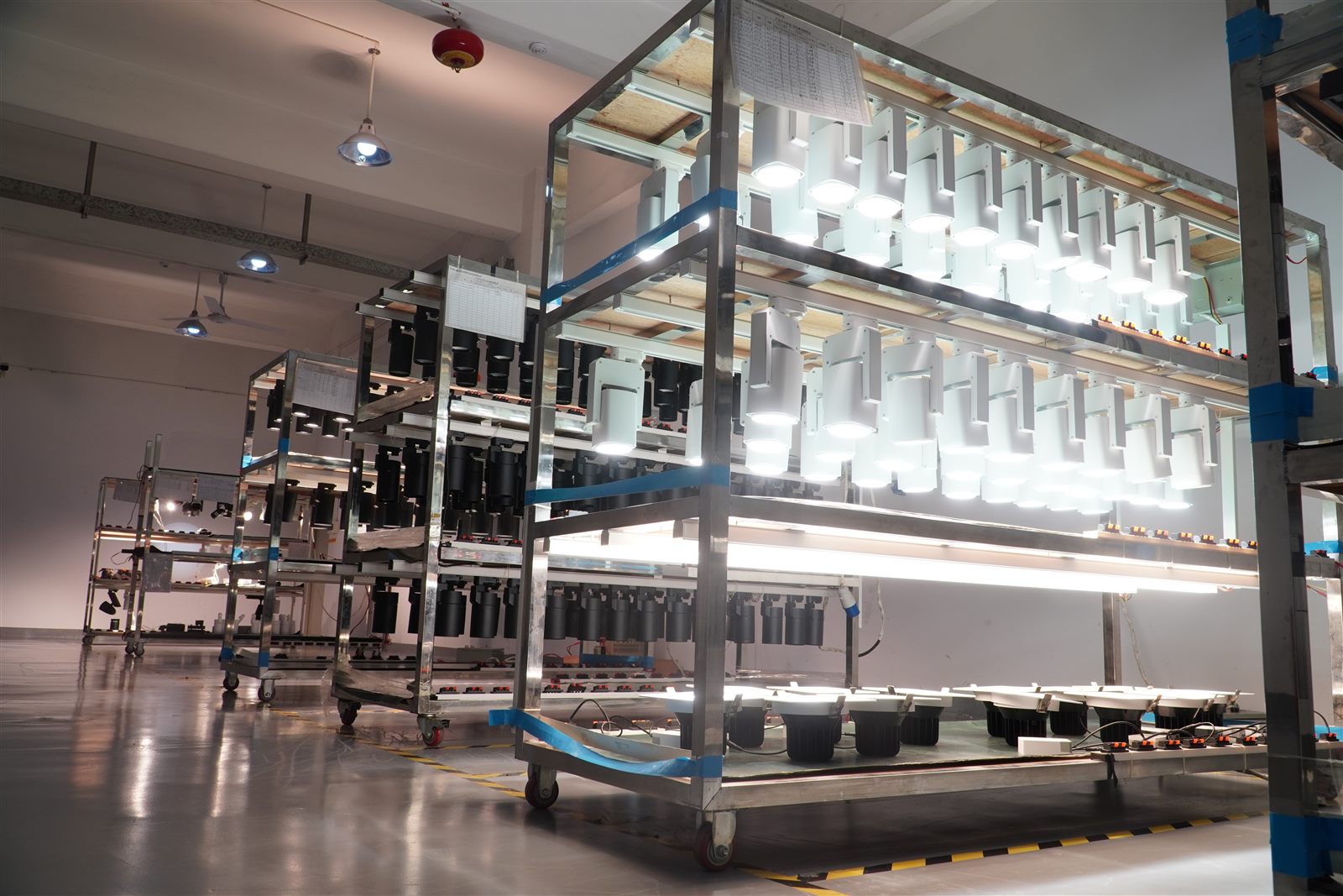 Burn-in aging test racks with track lights lit at ENCORE factory