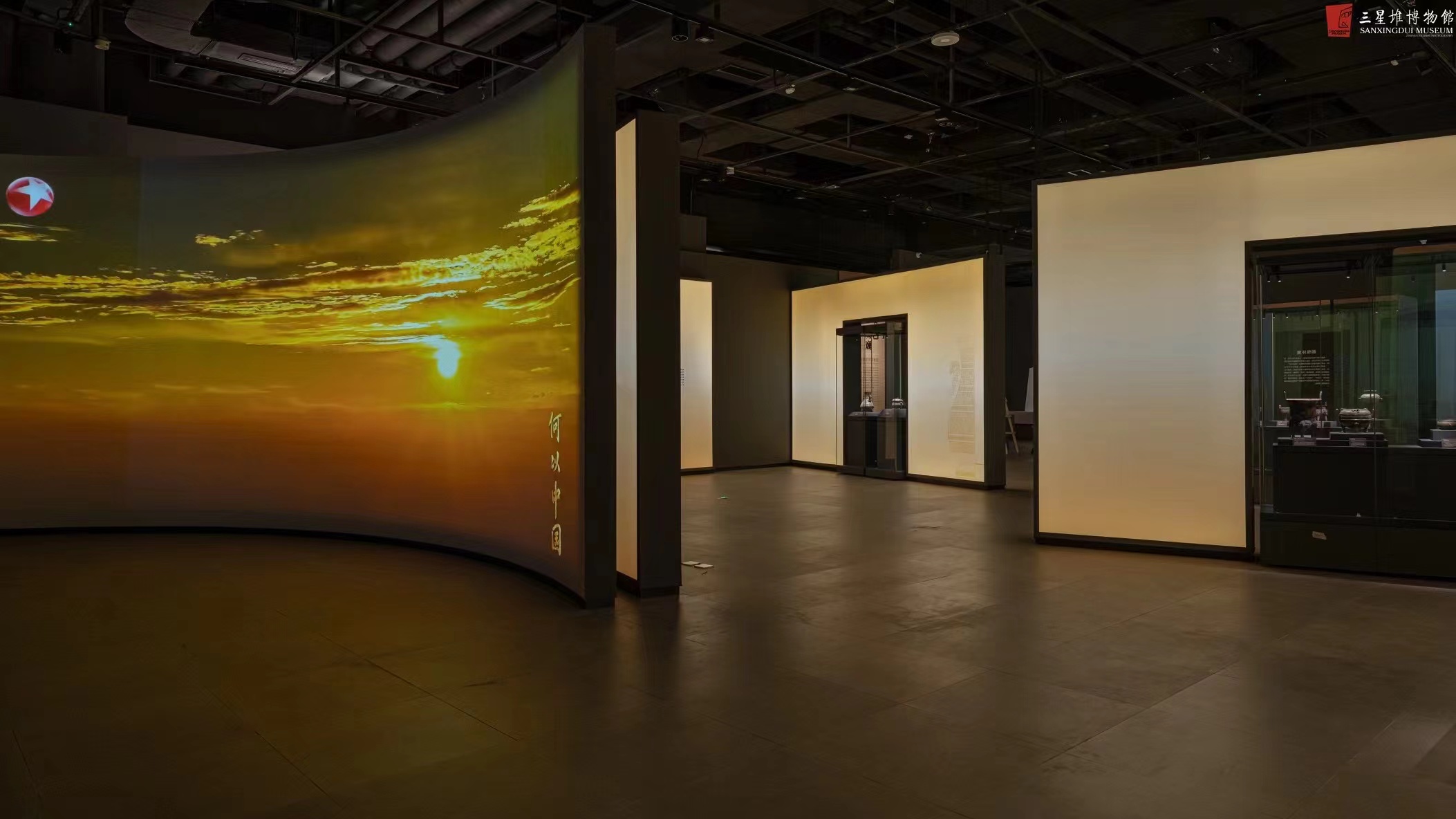 Sanxingdui exhibition hall with amber backlit walls and accent track spotlights on bronzes