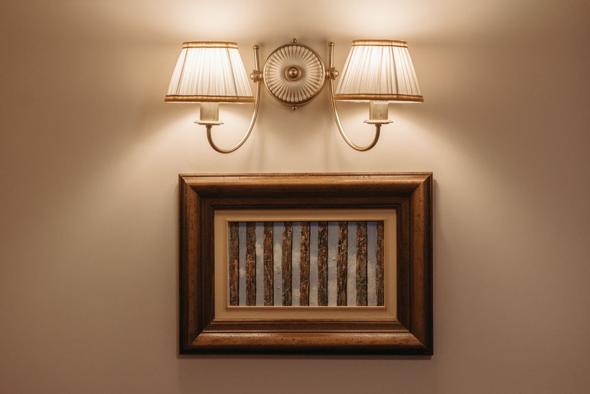 Softly lit wall light illuminating framed artwork in a warm home interior