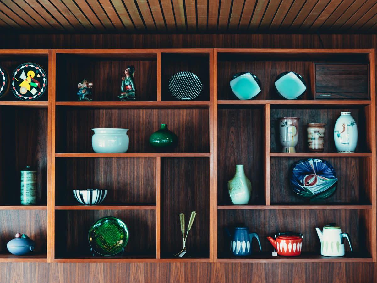 Glazed red and orange ceramics on a wooden shelf showing how a high R9 value keeps saturated red glazes rich instead of dull