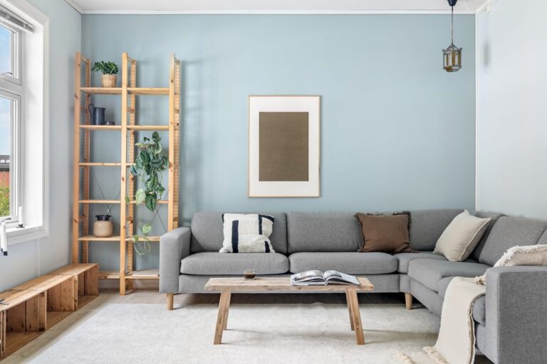 Cozy Scandinavian living room with a warm sofa and framed art lit by gallery lighting