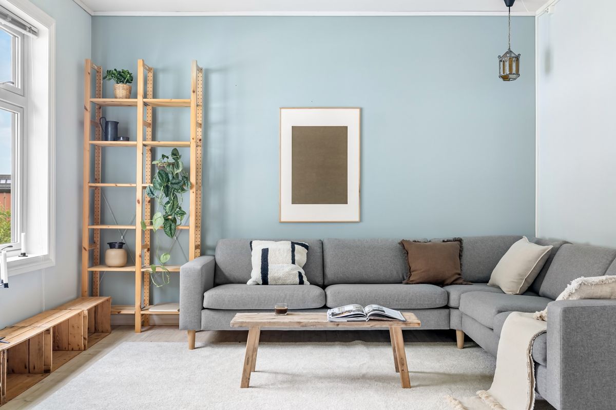 Cozy Scandinavian living room with a warm sofa and framed art lit by gallery lighting