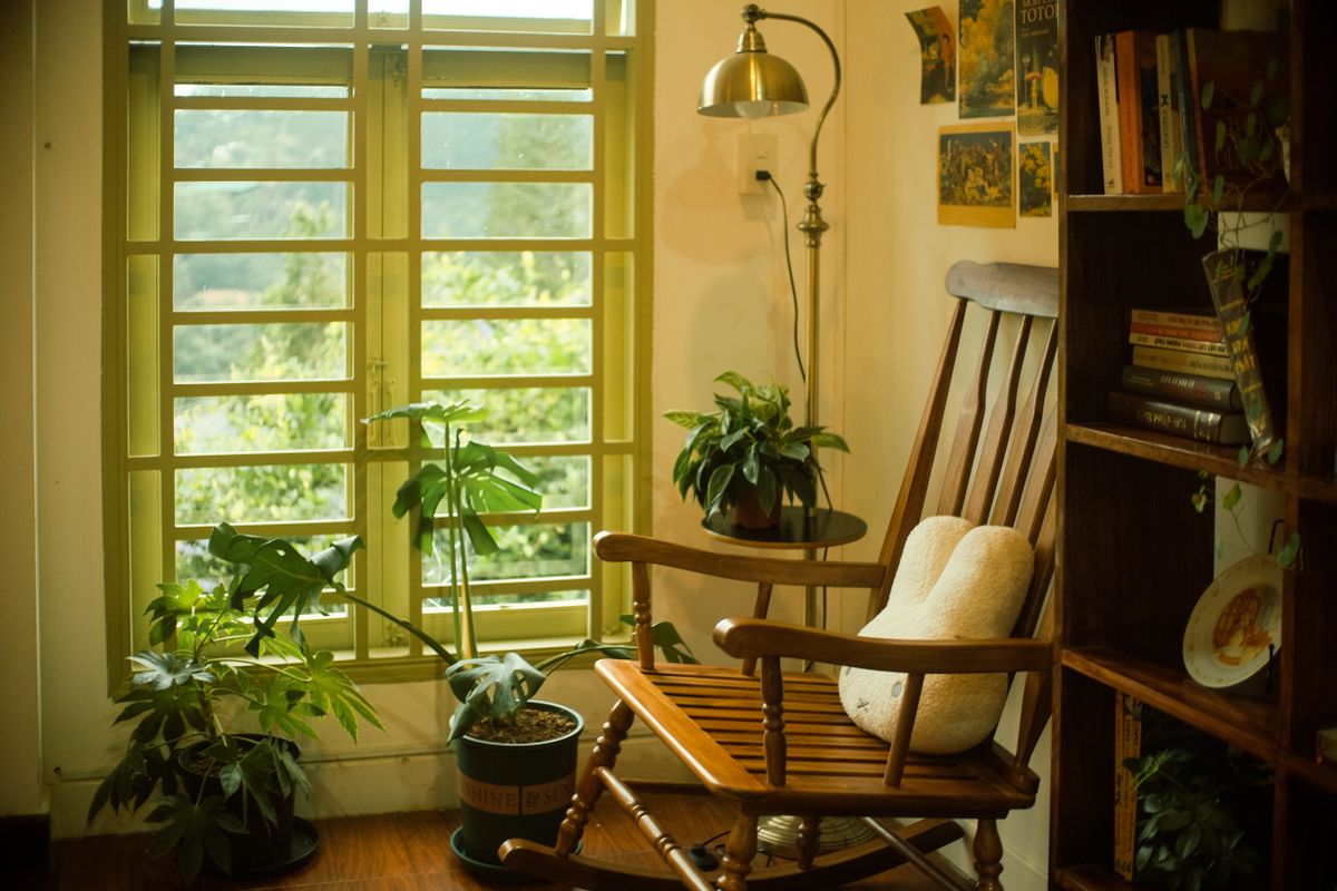 Cozy reading nook with wooden rocking chair and warm accent lighting on a plant shelf