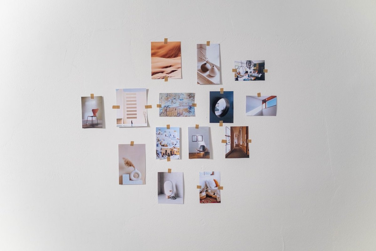 Small framed prints arranged on a white wall awaiting a controlled low luminance wall wash to raise background luminance