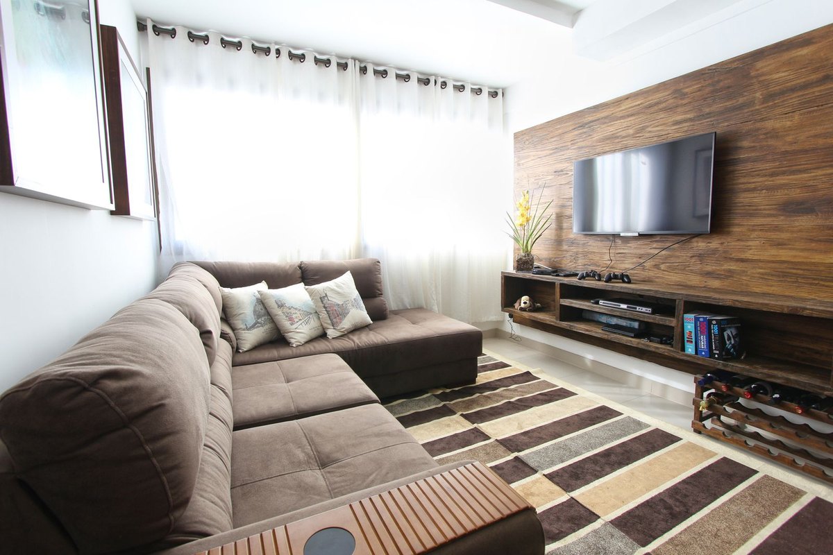 Evening living room interior where the ceiling is the darkest surface in view and layered lighting keeps bright sources outside the seating sight line