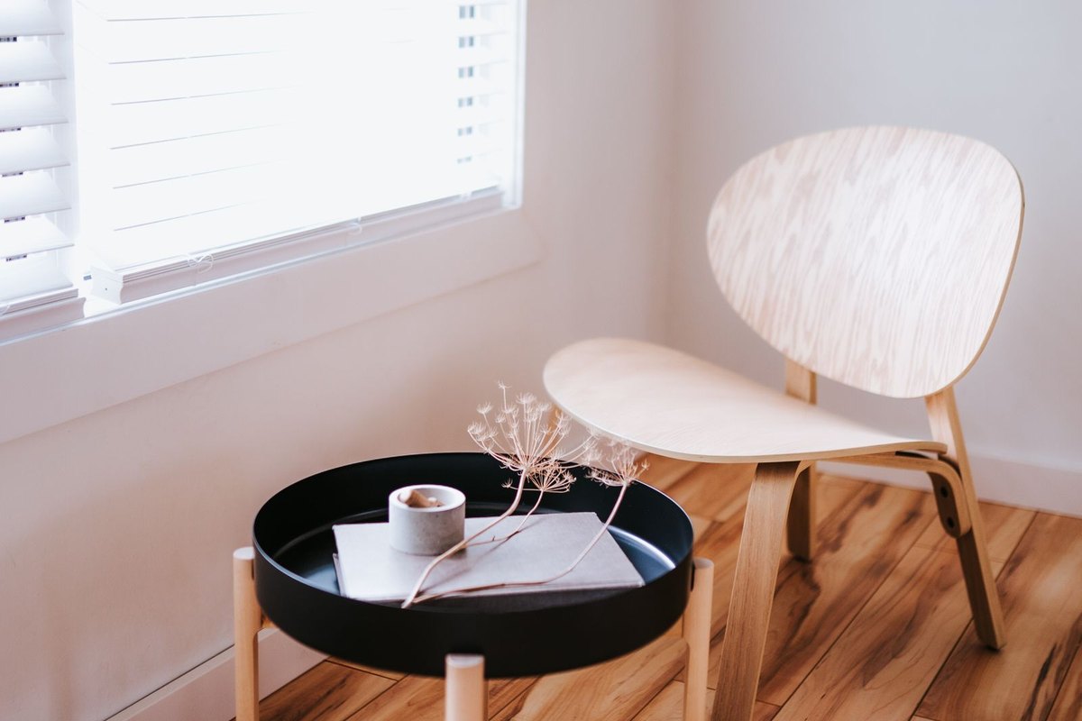 A single chair beside a bright window, the position in a room where discomfort glare is most often noticed and hardest to design away