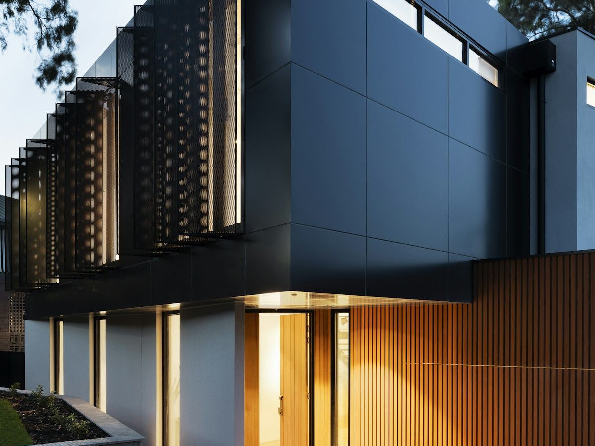 Dark modern glass house facade glowing warmly from glare-free interior lighting at night
