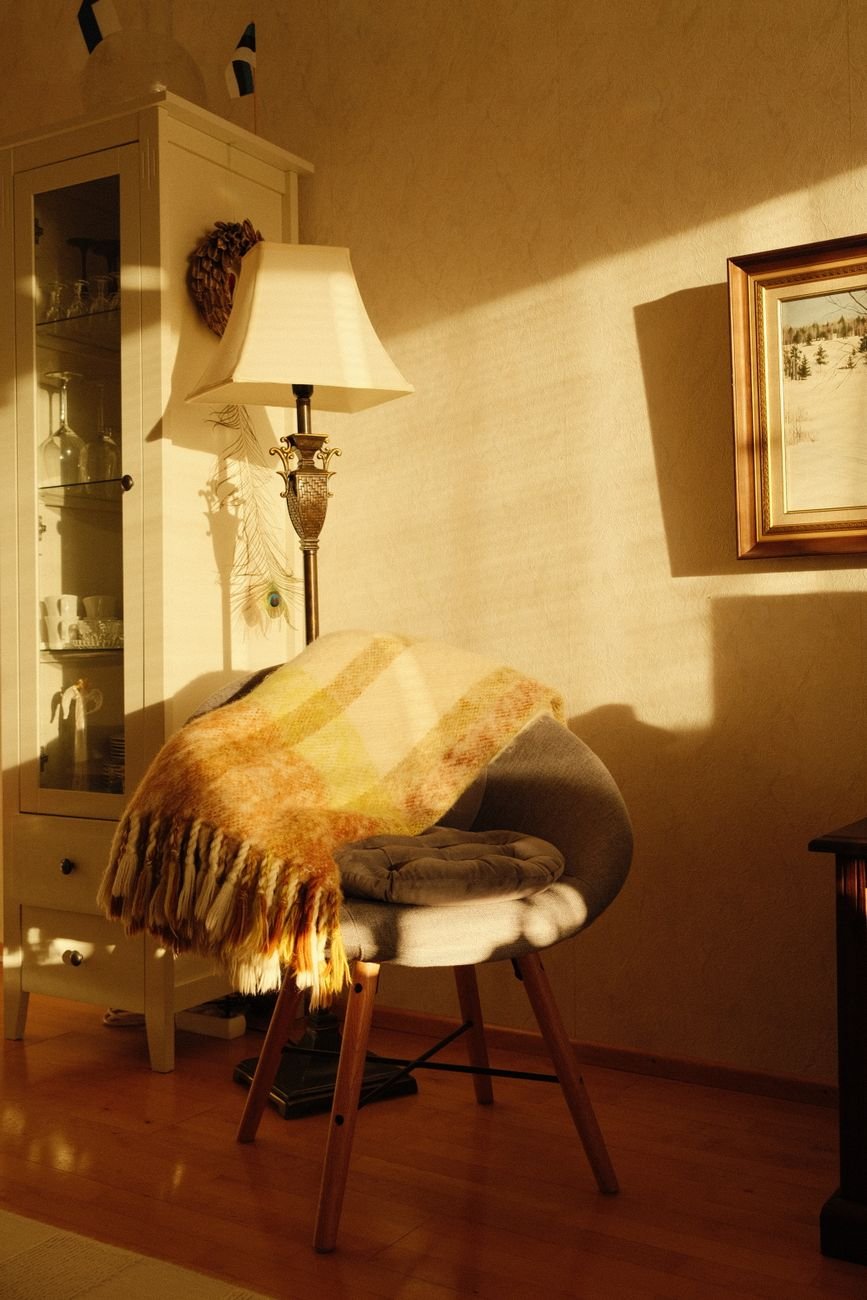 Cozy reading corner with warm lamp light and soft blanket providing optimal task lux levels