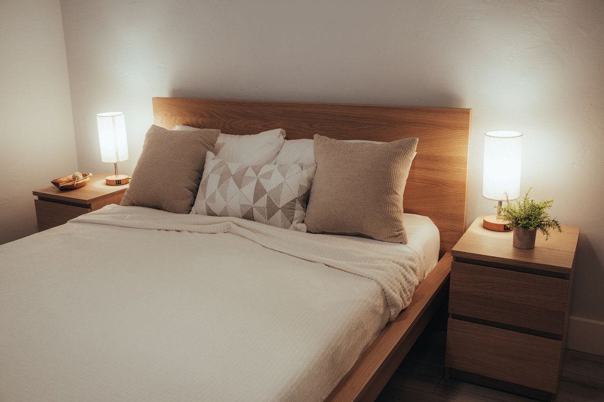 Minimal bedroom with two bedside lights and soft ambient lighting from wall washed track heads