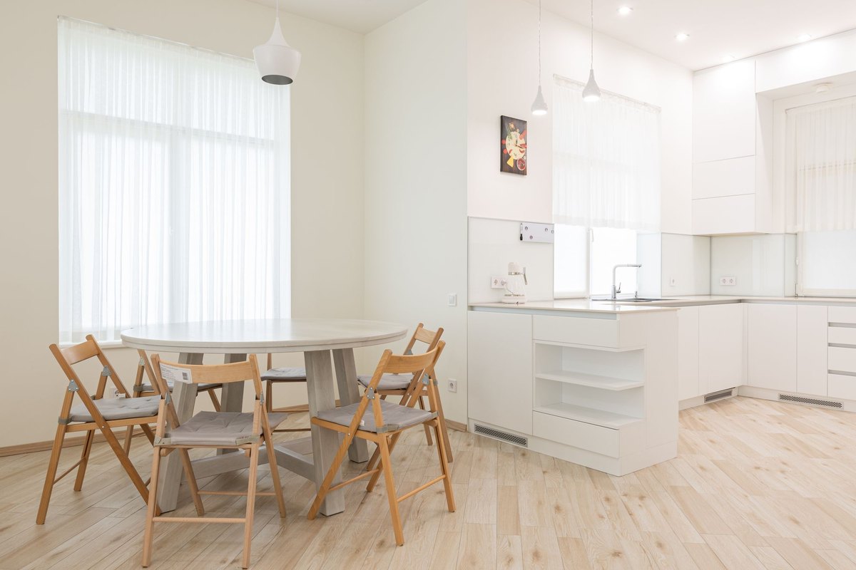 Minimal dining table with chairs showing track light heads spaced over the long edges of the table