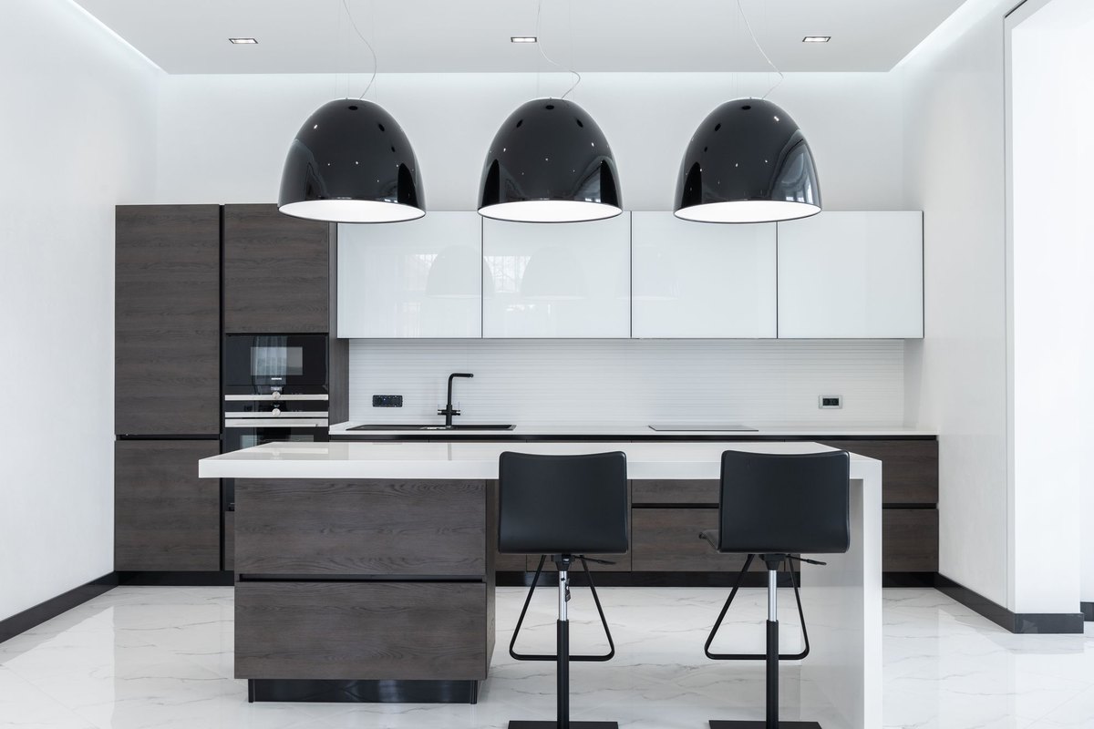 Modern kitchen with a marble island and two track light heads spaced above the worktop