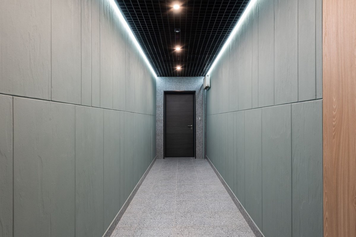 Long minimal corridor lit by evenly spaced recessed track lights along its axis