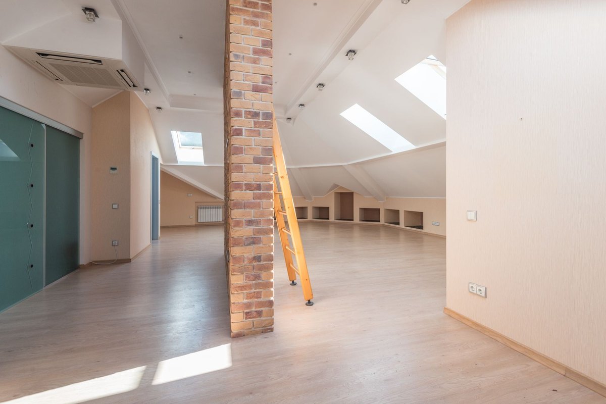 Attic room with a high ceiling lit from skylights where mounting height and therefore track light pitch varies