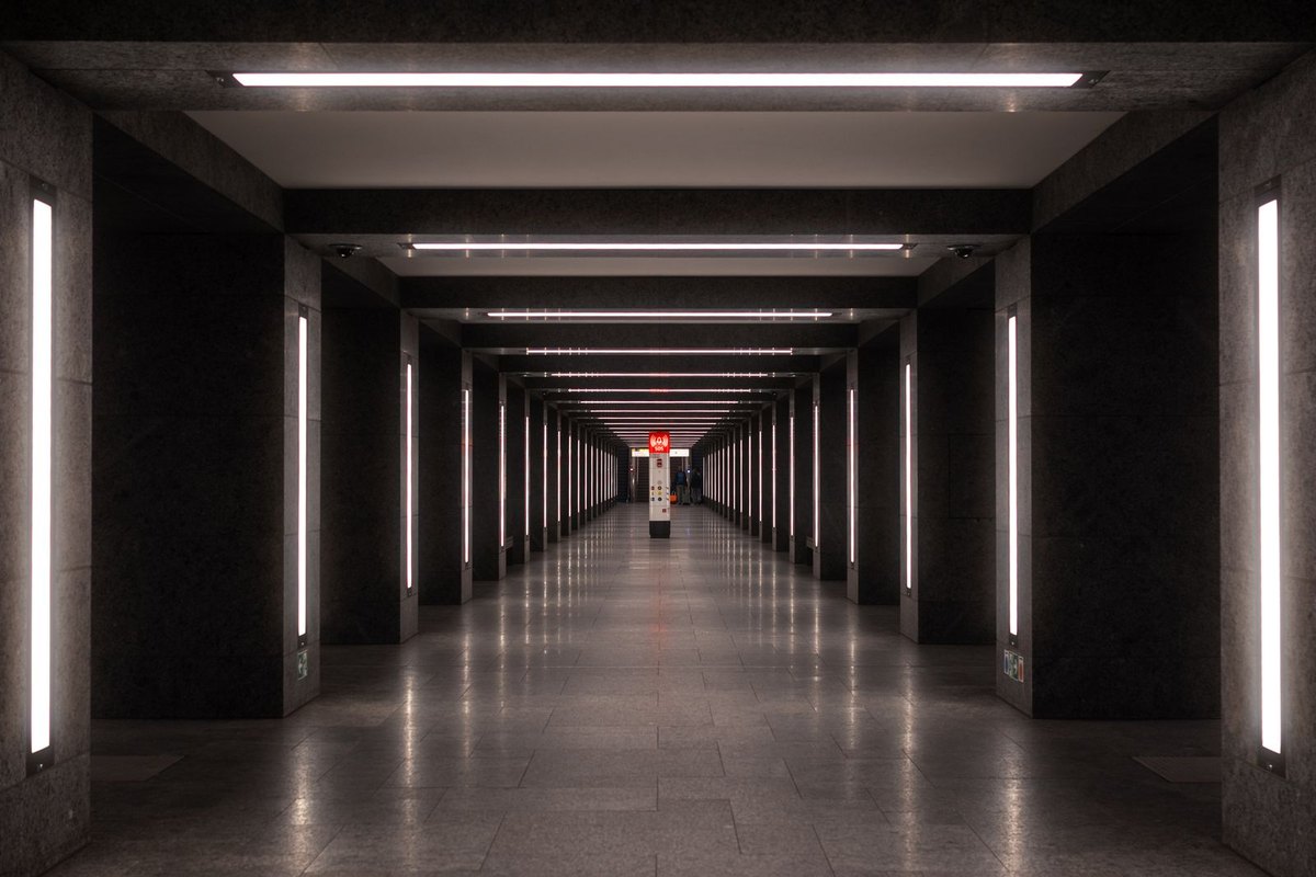 Symmetrical corridor with ceiling lights equally spaced along its axis illustrating pitch measured along the run