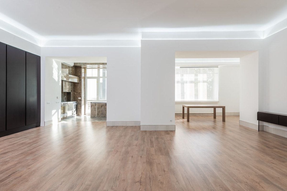 Empty room with wooden flooring before a track lighting layout is set out from beam angle and height