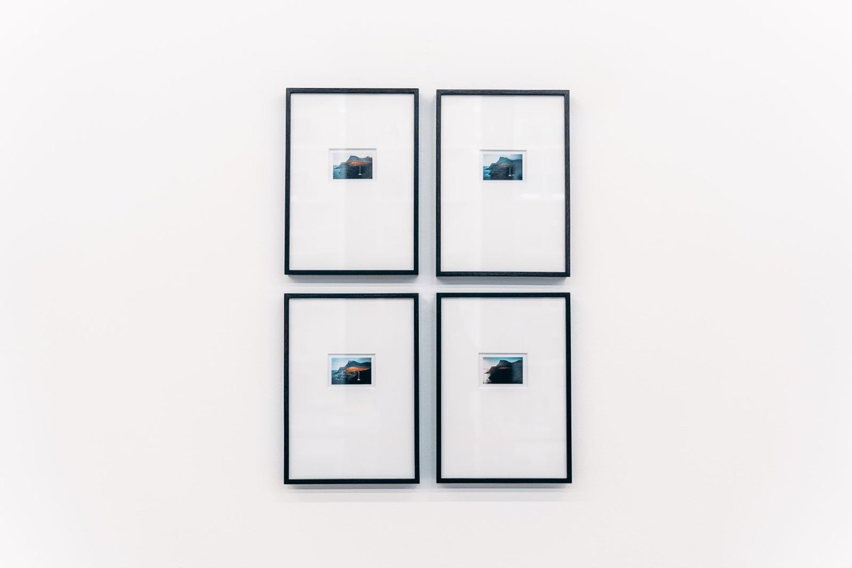 Four small black frames on a white wall each lit by its own narrow accent head at 20 percent overlap