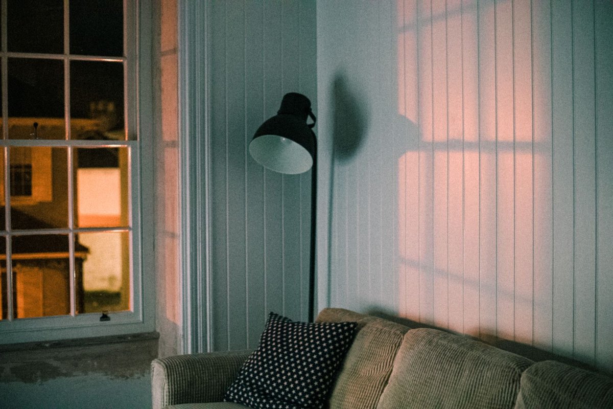 Warm evening living room lit low with the ceiling staying the darkest surface to control glare from ceiling lights