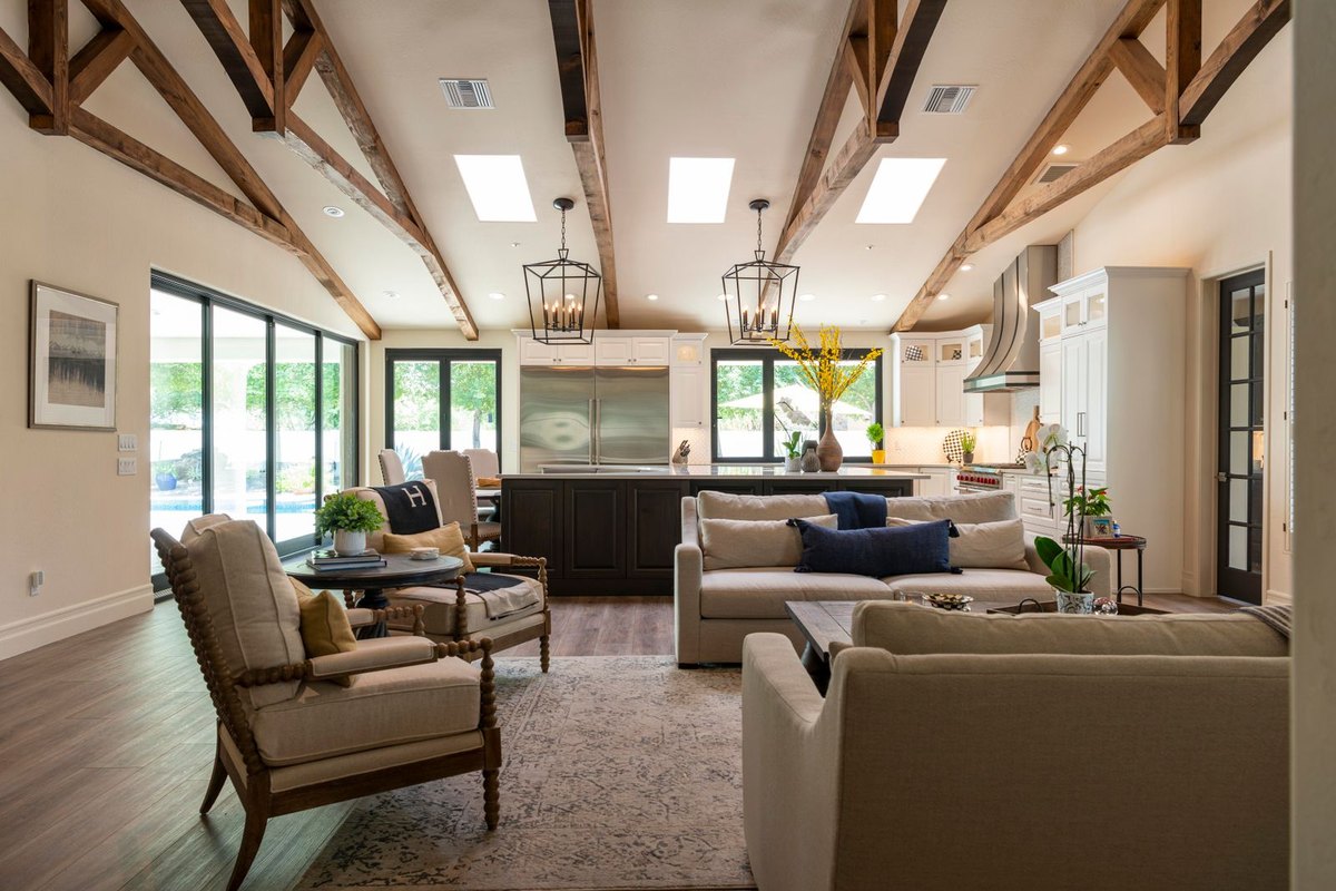 Open plan room with exposed beams and a tall ceiling showing spaced ceiling lights sized for the height